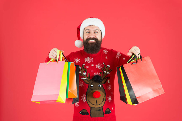 落ち着いて、続けてください。髭の男は買い物袋を持っている。ハッピーヒップスターは紙袋を運ぶ。カラフルなバッグで休日の購入。冬の販売と割引。クリスマスと新年の準備。バッグを掴め - 写真・画像