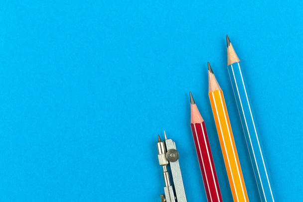 最初の日、コンセプト、鉛筆と青いオフィスの机の上にコンパスを描くフラットレイアウトの背景に学校の機器足 - 写真・画像