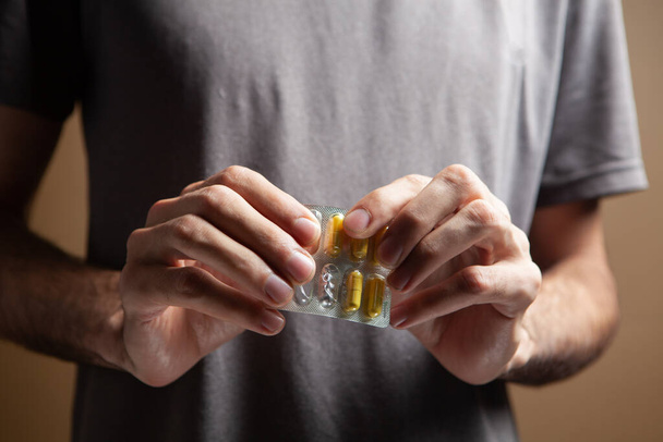 een man met een pil in zijn hand - Foto, afbeelding