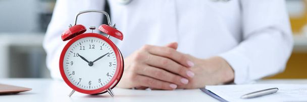 Doctor therapist sitting in office in front of red alarm clock closeup - Foto, imagen