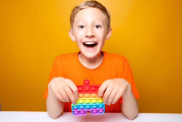 il bambino tiene un colorato silicone anti-stress palle giocattolo che scoppiano davanti a lui - Foto, immagini