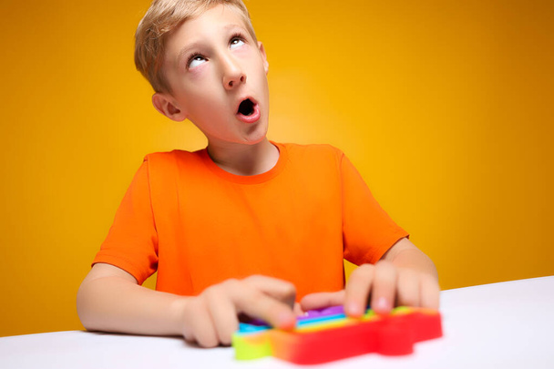 το αγόρι γύρισε τα μάτια του στην ευχαρίστηση να παίξει με ένα παιχνίδι αντι-στρες σιλικόνης - Φωτογραφία, εικόνα