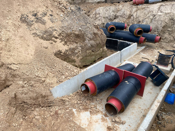 Grote industriële moderne nieuwe grote diameter polyethyleen kunststof waterleidingen liggen in een put ondergronds op een bouwplaats tijdens een waterleiding reparatie. - Foto, afbeelding