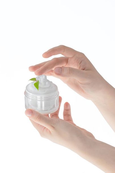 a jar of cream in female hands on a white background isolate, the concept of skin care, spa, massage, natural ingredients, care for the health of the skin of the hands, face and body - Photo, Image