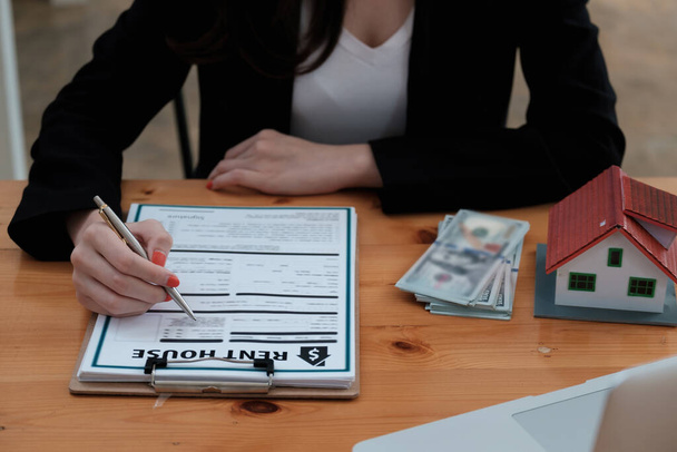 Após um acordo com um corretor, uma mulher assina um contrato para alugar uma casa - Foto, Imagem