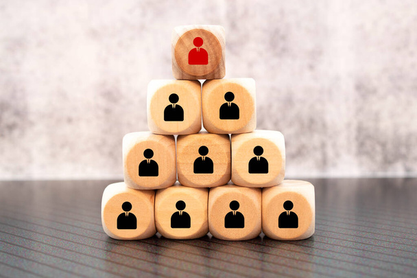 Leiderschap en human resources concept met houten blokken met zakenman silhouetten gestructureerd in een piramide - Foto, afbeelding