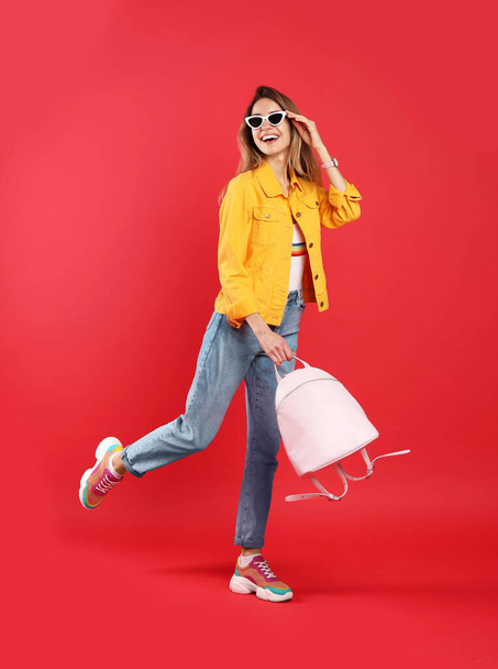 Happy woman with backpack on red background - Photo, Image
