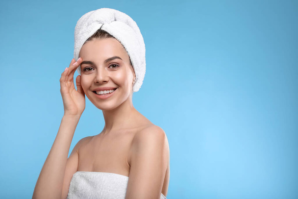 Happy young woman with towel on head against light blue background, space for text. Washing hair - Φωτογραφία, εικόνα