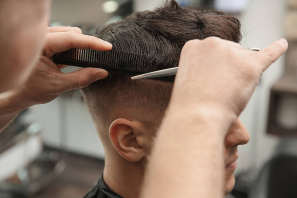 Professional barber making stylish haircut in salon, closeup - Fotoğraf, Görsel