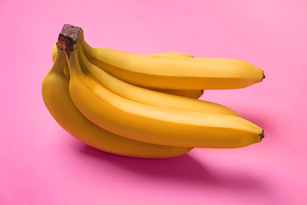 Bunch of ripe yellow bananas on pink background, closeup - Foto, afbeelding