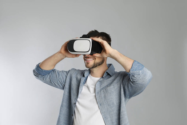 Man using virtual reality headset on grey background - Fotó, kép
