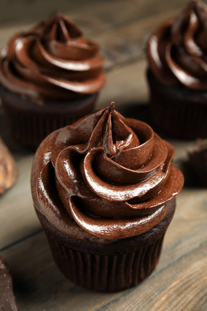 Delicious chocolate cupcake with cream on wooden table - Zdjęcie, obraz