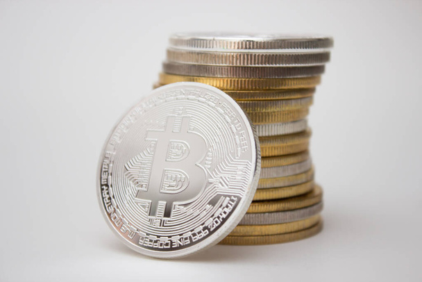 One silver bitcoin and stack of bitcoins over white background - Valokuva, kuva