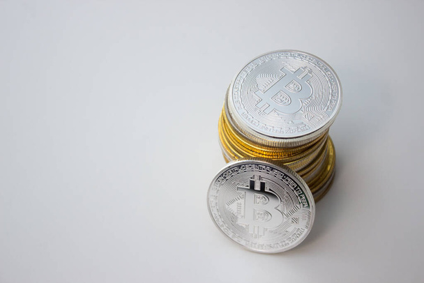One silver bitcoin and stack of bitcoins over white background - 写真・画像