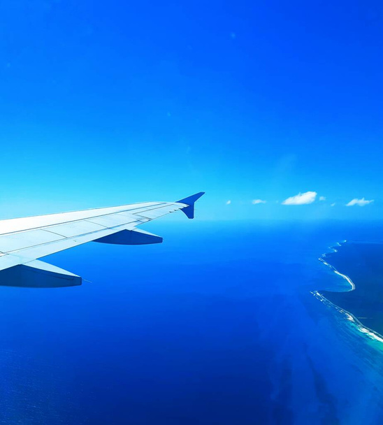 Pohled z okna na ocas letadla na modré obloze s mraky  - Fotografie, Obrázek