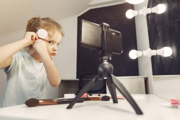 Cute little blogger with cosmetics recording video at home - Fotoğraf, Görsel