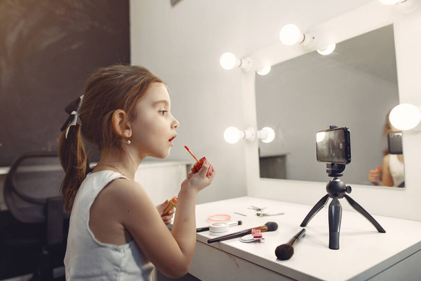 Cute little blogger with cosmetics recording video at home - Fotó, kép