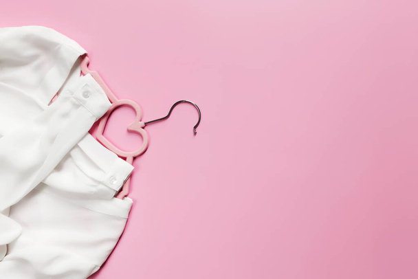 Черная пятница, концепция индустрии одежды на розовом фоне лежала с розовым платьем висящим и белым блузчным платьем с формой сердца висящим на висячем - Фото, изображение