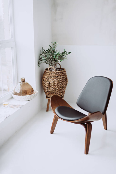 Moderne fauteuil in zwart leer en hout in een wit hok interieur. Ontwerper stoel. Zachte selectieve focus. - Foto, afbeelding