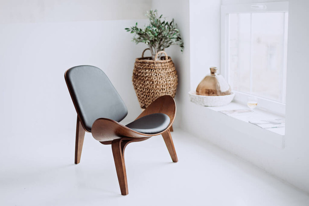 Poltrona moderna em couro preto e madeira em um interior loft branco. Cadeira de design. Foco seletivo suave. - Foto, Imagem
