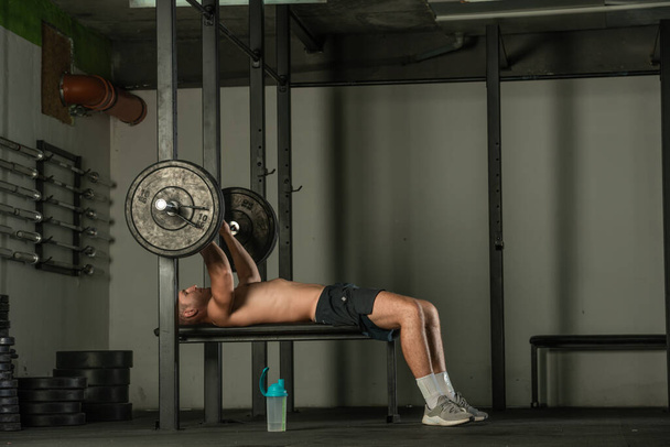 fisiculturista muscular atlético fazendo exercício supino em ambientes fechados em um ginásio moderno. - Foto, Imagem