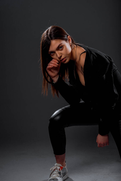 Körperbild eines coolen modernen Mädchens mit schwarzem Oberteil und schwarzer Latexhose - Foto, Bild