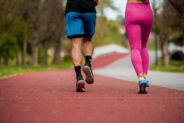 Portrait of a young happy couple racing each other and having some fun at a running track - Photo, Image