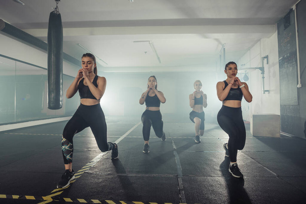 Група спортсменів у спортивному одязі роблять лаунж вправи в спортзалі з правою ногою
 - Фото, зображення