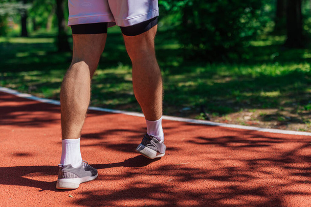 Foto de cerca de zapatillas de correr masculinas en una pista de carreras en el parque - Foto, Imagen