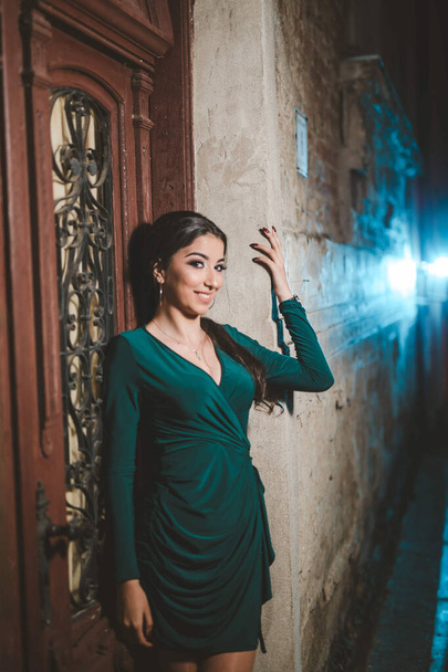 A vertical shot of a white Caucasian woman wearing a green evening dress and posing for a picture - Fotó, kép