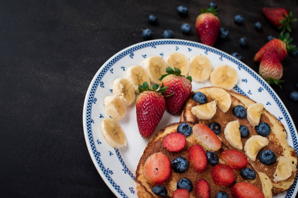 A closeup shot of delicious waffles with strawberry, banana and blueberries - 写真・画像