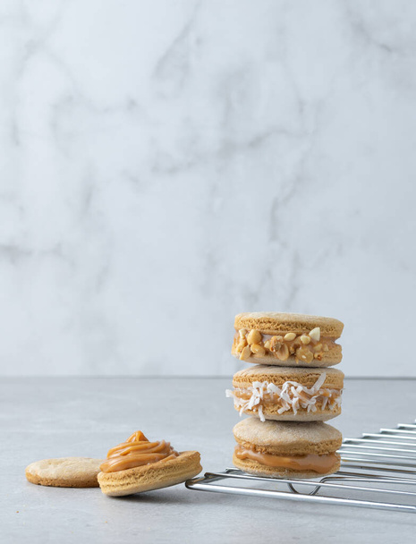 A vertical shot of delicious macarons of various fillings stacked on a grid - 写真・画像