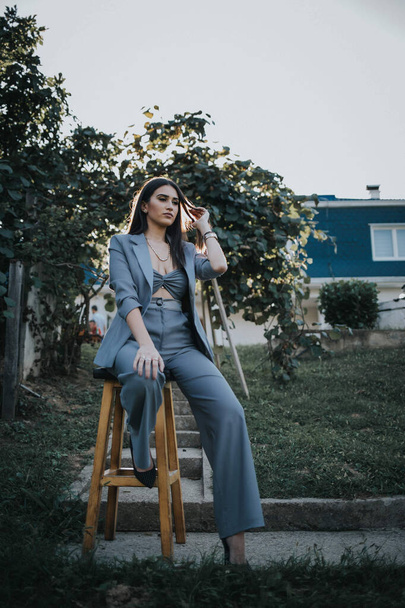 A sexy female from Bosnia and Herzegovina in a trendy blue suit sitting on a wooden bar stool - Foto, immagini