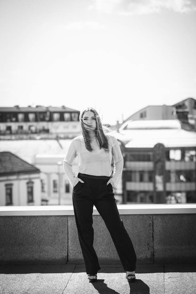 A shallow focus of an adult Caucasian woman wearing a suit and posing on a rooftop - Foto, imagen
