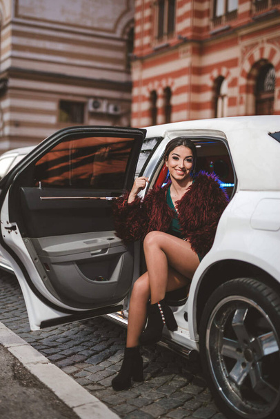 A young Caucasian dark hair female from Bosnia and Herzegovina posing in a car - Фото, изображение