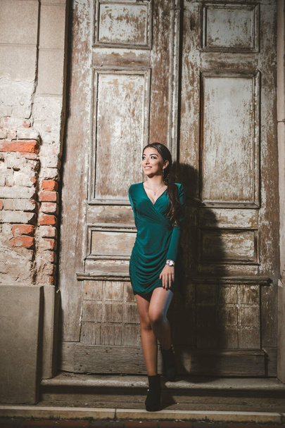 A young sexy Caucasian girl posing in front of an old weathered wooden door - Zdjęcie, obraz
