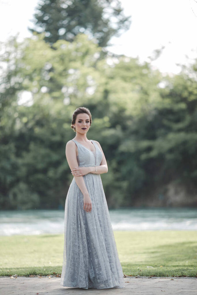 Egy fiatal, vonzó kaukázusi nő sminkkel, gyönyörű estélyi ruhában és pózban a szabadban. - Fotó, kép