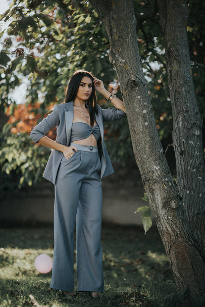 A sexy female from Bosnia and Herzegovina in a trendy blue suit posing in the forest - Zdjęcie, obraz