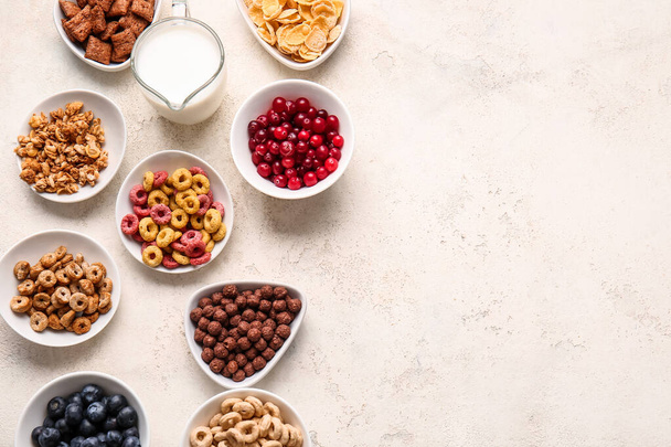 Bowls with different cereals, berries and milk on light background - Foto, afbeelding