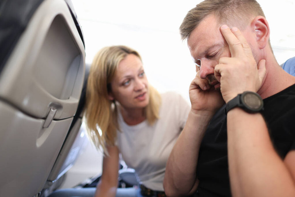 Fejfájásos férfi csukott szemmel a repülőn. - Fotó, kép