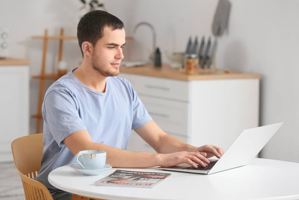 Komea mies käyttää kannettavaa tietokonetta kotona - Valokuva, kuva