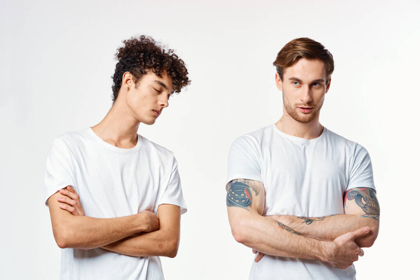 Двоє веселих друзів у білих футболках стоять пліч-о-пліч обрізаним видом
 - Фото, зображення