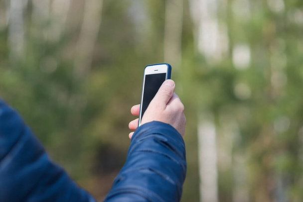 Jeden 40-latek ze swoim smartfonem szuka sygnału odbioru w wiosennym lesie.. - Zdjęcie, obraz