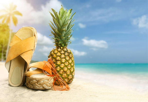 Elegantes accesorios de playa con piña sobre arena en un resort tropical - Foto, imagen