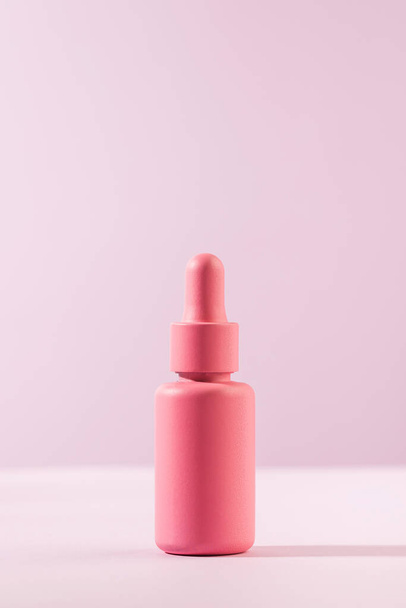 A mockup of a pink dropper with a facial serum on a pink background. Trends in facial skin care. Copy space. - Valokuva, kuva