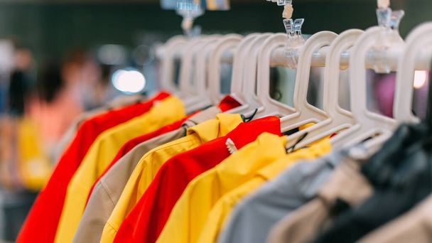 Φθινοπωρινά μπουφάν διαφόρων χρωμάτων κρέμονται σε μια κρεμάστρα στο κατάστημα. - Φωτογραφία, εικόνα