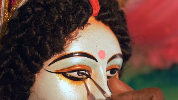Mani di un pittore indiano che disegna gli occhi della statua dell'idolo indù Ma Durga. Primo piano della mano di un artigiano che dipinge gli occhi della scultura in argilla della dea Durga per il festival Durga Puja - Filmati, video