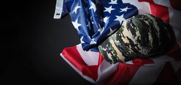 Chapeau militaire ou sac posé avec drapeau américain. Casque ou chapeau de soldat avec drapeau national américain sur fond noir. Représenter le concept militaire par objet de camouflage et drapeau des États-Unis. - Photo, image