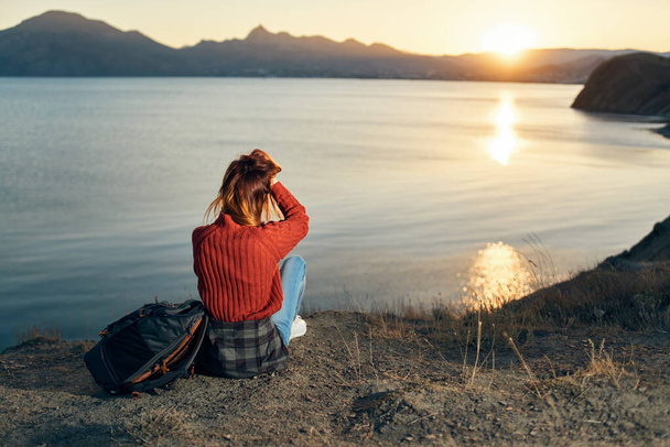 um viajante em uma camisola Senta-se na praia e observa o pôr do sol - Foto, Imagem