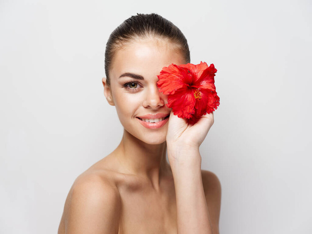 cheerful woman with red flower bared shoulder cropped view clear skin - Foto, Imagen